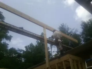 Carpenter setting a ridge beam over a new addition frame — Ice Dam Removal by Roofing Brothers in Chittenango