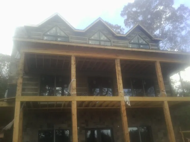 Dormers and porch framing on a large log home under construction — Roof Coating work by our crew in Chittenango