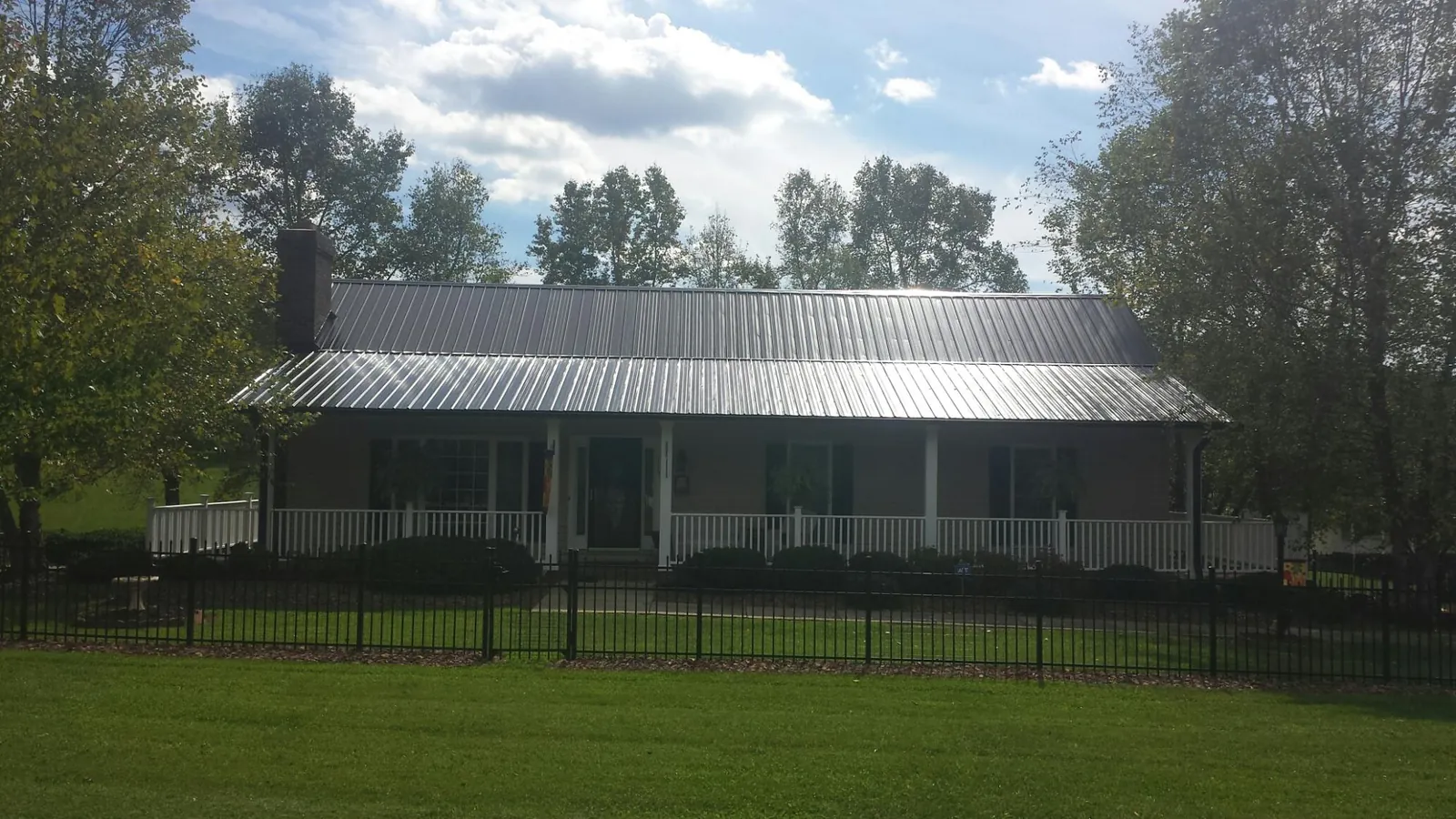 Gray metal roof on a brick ranch with a full width front porch — Gutter Guard Installation work by our crew in Chittenango