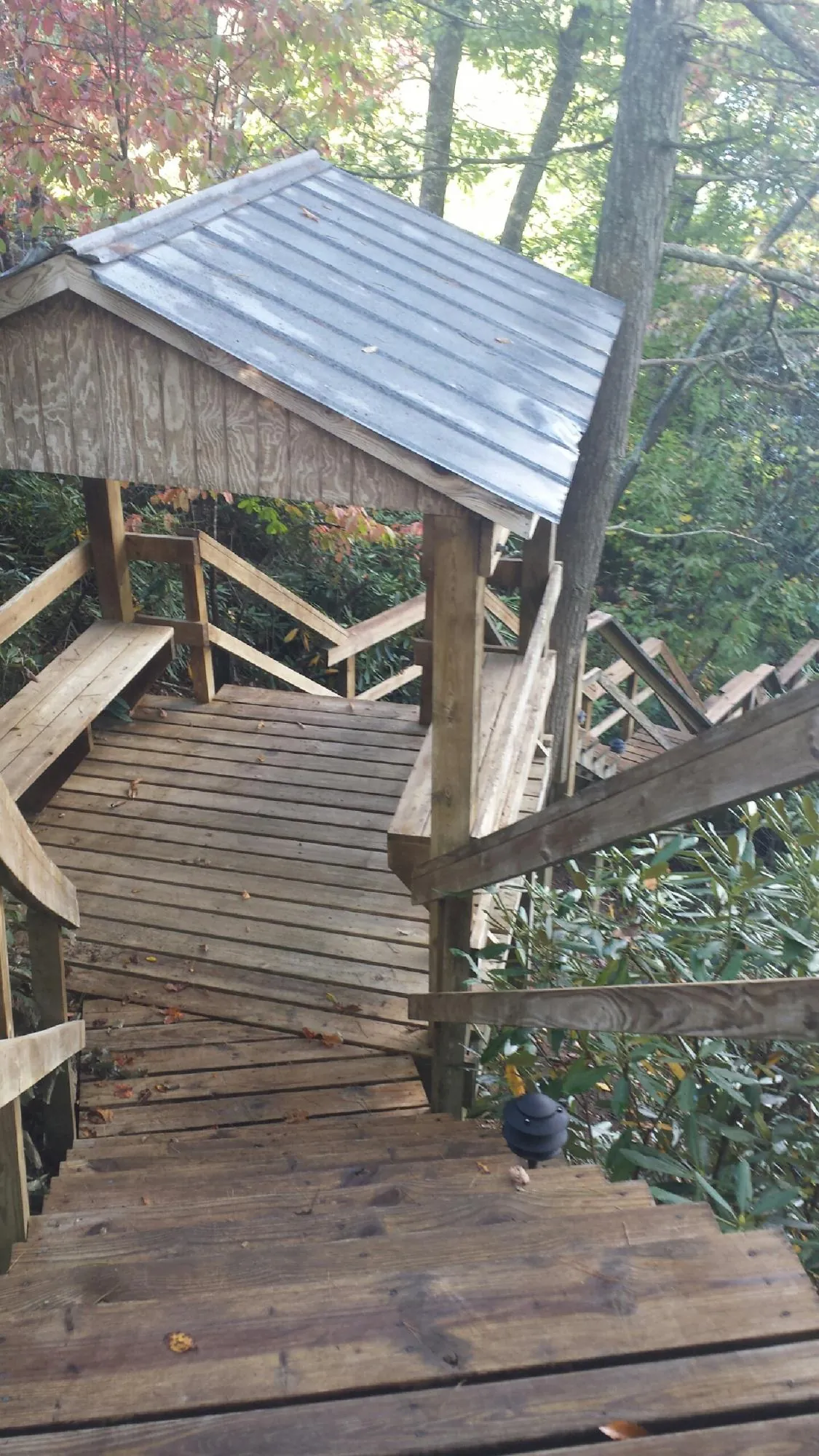 Metal roofed shelter over wooden steps on a wooded walkway — Skylight Repair & Installation work by our crew in Chittenango